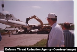 Unidentified men look on as one of Ukraine's supersonic Tu-160 bombers is broken up.