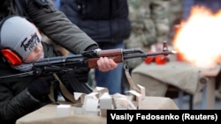 An officer of Belarus's Interior Ministry teaches a child to fire an automatic weapons in March 2020