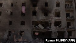 A woman cleans debris from a heavily damaged apartment building following a Russian aerial attack on Selydove in eastern Ukraine.