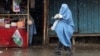 An Afghan woman in a burqa walks along a street.