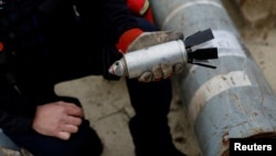 A Ukrainian soldier holds a defused cluster bomb from an MSLR missile in Kharkiv on October 21, 2022.