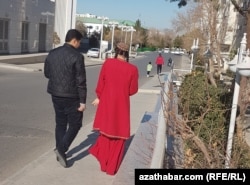 A young woman and man walking on the street in Ashgabat.