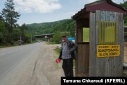 A Georgian worker directs traffic outside a work camp where construction crews sleep and new concrete is poured for the highway project.