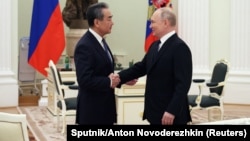 Russian President Vladimir Putin (right) shakes hands with China's top diplomat, Wang Yi, during a meeting in Moscow on February 22.