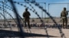 U.S. soldiers watch migrants waiting on the U.S. side of the border to be allowed to go to a CBP processing center in El Paso, Texas.