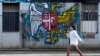 A girl walks by a mural on a wall that shows the Serbian (left) and Russian coats of arms in Belgrade.