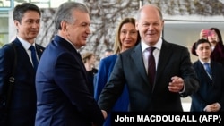 German Chancellor Olaf Scholz (right) shakes hands with Uzbek President Shavkat Mirziyoev upon the latter's arrival in Berlin on May 2. 