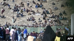 Afghan refugees sit on a hilltop outside the International Organization for Migration office as they wait for registration upon their arrival from Pakistan near the border in Nangarhar Province on November 12.