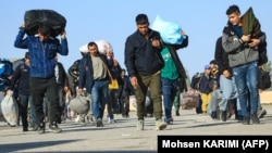 Afghan immigrants deported back from Iran carry their belongings at a registration center in the Islam Qala border town of the western Herat Province. (file photo)