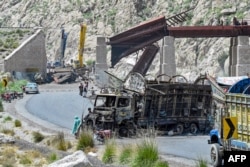 Residents stand beside a charred vehicle near a collapsed railway bridge the morning after a blast caused by Baluch separatist militants at Kolpur in the Bolan district of the southwestern Balochistan Province in August 2024.