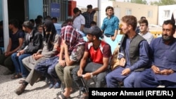 Afghans expelled from Iran wait outside the office of the International Organization of Migration in the western Afghan province of Herat. (file photo)