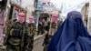 Taliban security personnel patrol a street as a burqa-clad Afghan woman walks by in Badakhshan Province (file photo).