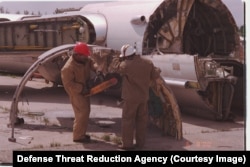 A strategic bomber being broken up by workers with a buzz saw.