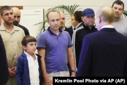 Russian President Vladimir Putin (foreground, right) speaks with the group of Russians returned from Western incarceration in a historic prisoner swap on August 1. Accused Russian-Spanish spy Pablo Gonzalez, who roamed the EU and South Caucasus as a journalist, stands in the background, second left.