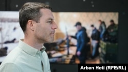 American photojournalist Brendan Hoffman views the exhibition as a photo taken by him on the second day of the invasion is seen in the background.