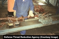 A worker with lengths of copper wiring in a photo labeled "silo dismantlement project."