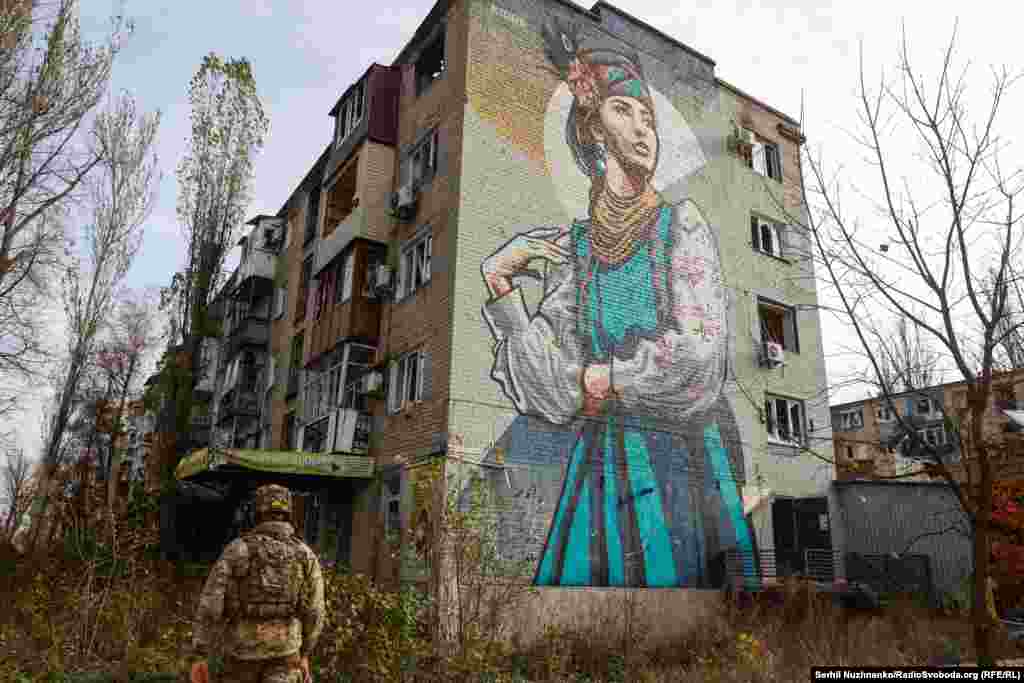 A soldier walks beneath a mural in the embattled town of Avdiyivka in the Donetsk Region in November 2023.&nbsp;