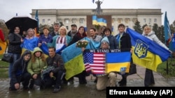 People hold national flags and pose for a photo as the city marks one year since Ukraine retook the city of Kherson from occupying Russian forces, in central Kherson on November 11.