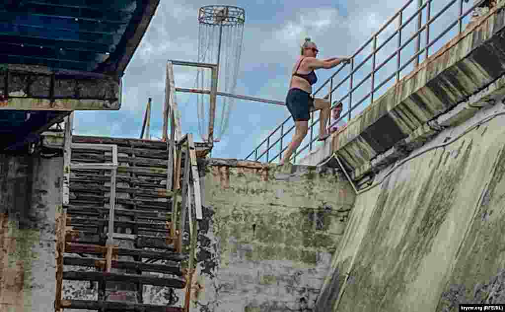 A woman climbs up to the aging boardwalk. Russian President Vladimir Putin was forced to evacuate his warships to the relative safety of Novorossiysk following the relentless Ukrainian attacks.