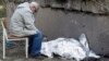 A relative sits next to the covered body of a young Ukrainian girl who was killed in a Russian missile strike on Kyiv on June 1. 