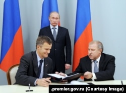 Russian President Vladimir Putin (standing) attends the signing of an agreement on strategic cooperation between then-Rosneft CEO Eduard Khudainatov (right) and then- Statoil ASA CEO Helge Lund on May 5, 2012.