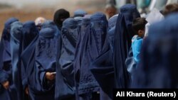 Displaced Afghan women wait in line to receive cash aid in Kabul. (file photo)