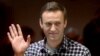 Aleksei Navalny waves from inside a glass cell during a court hearing in Moscow on February 20.