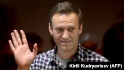 Aleksei Navalny waves from inside a glass cell during a court hearing in Moscow on February 20.