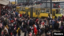 Ukrainians fleeing the Russian invasion wait to board a train to Poland outside the train station in Lviv.