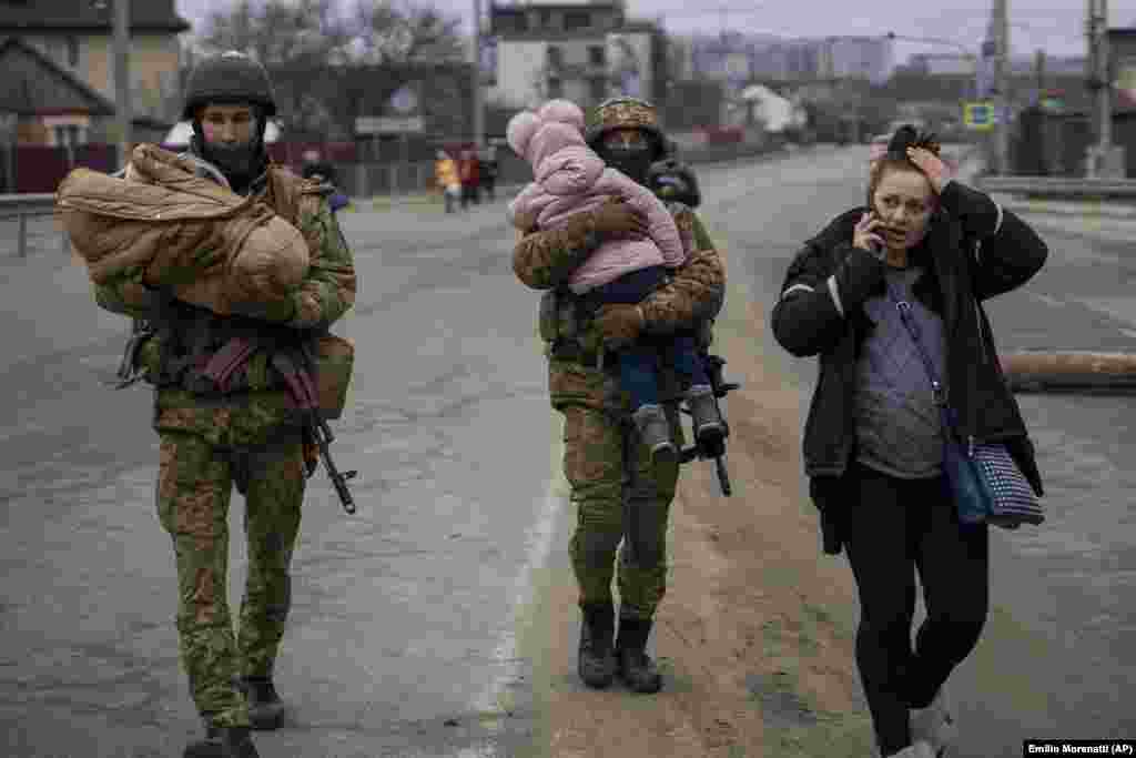 Ukrainian soldiers carry babies as they help a fleeing family to find a vehicle after crossing the Irpin River in the outskirts of Kyiv on March 5.