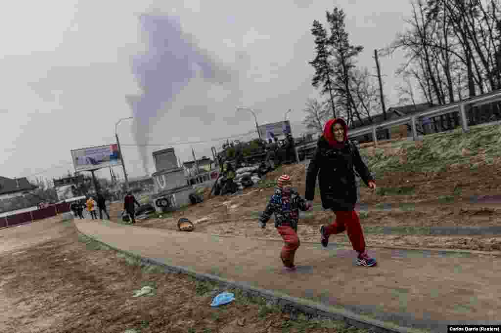 Local residents run for cover on March 6 as they escape from the town of Irpin, after heavy shelling on the only escape route used by locals, while Russian troops advanced toward the capital, Kyiv.