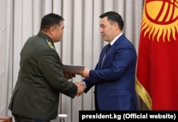 Japarov (right) shakes hands with Tashiev in parliament on October 13, 2021.