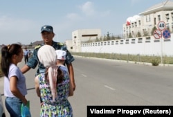 A member of Kyrgyz security forces addresses passersby near the site of a bomb blast outside China's embassy in Bishkek on August 30, 2016.