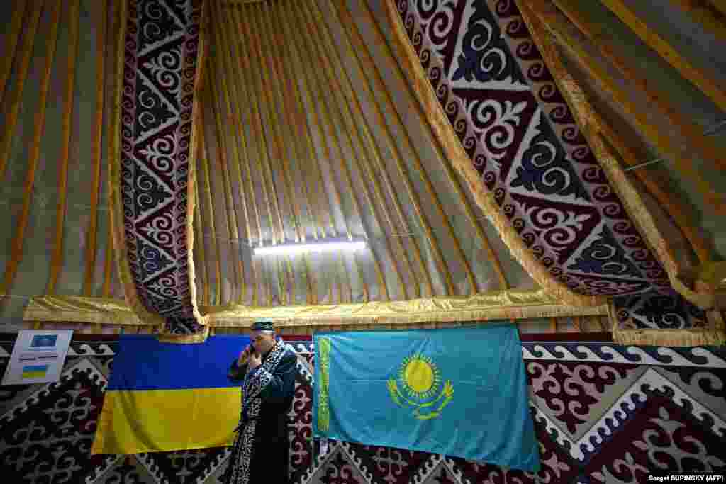 Dressed in traditional attire,&nbsp;a Kazakh man stands next to the flags of Ukraine and Kazakhstan before welcoming residents of Bucha. Inhabitants of the city endured a brief but brutal occupation by Russian forces at the start of the invasion. The Russian Army is accused of committing multiple war crimes in Bucha during the early weeks of the war before the town was retaken by Ukrainian forces.