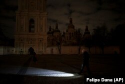 A woman walks with a flashlight during a power outage in Kyiv on December 14.