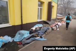 A Ukrainian police officer walks past the bodies of people killed by shelling as they lie covered outside a hospital in Mariupol on March 15.