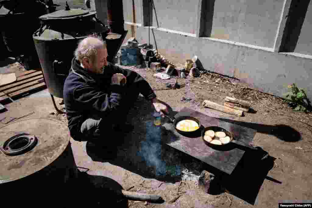 A man cooks over an open fire outside the bunker of a factory in Severodonetsk on April 27.&nbsp;