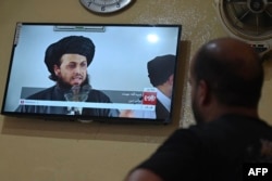 In this picture taken in September 2021, a man at a restaurant watches a live television broadcast showing a religious scholar speaking in Kabul.