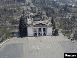 The destroyed theater in Mariupol with the word "children" written in Russian in large white letters on the pavement in April 2022.