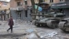 A resident of Mariupol walks past tanks used by pro-Russian separatist forces in May. 