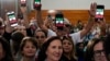 People hold up phones displaying the words "Free Iran" as President Joe Biden addresses a crowd in San Diego on November 3.