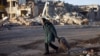 An elderly woman pulls a trolley bag past a destroyed building in Bakhmut in Ukraine's Donetsk region in December 2022. 