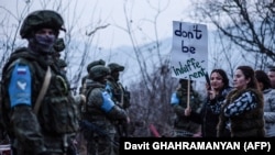 Protesters stand in front of Russian peacekeepers on the road outside Stepanakert, the de facto capital of Nagorno-Karabakh, on December 24, 2022. 