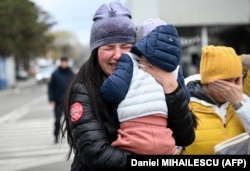 A Ukrainian refugee holding her child cries after arriving at the Siret border crossing between Romania and Ukraine on April 18, 2022.