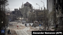 Residents of Mariupol who have not yet fled walk down an avenue of the city amid the wreckage of war on April 12.