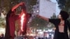 A woman sets fire to a headscarf in Iran during a recent protest.