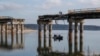 Civilians cross the Siverskiy Donets River by boat under a damaged bridge in the liberated city of Stariy Saltiv east of Kharkiv. It's estimated that Ukraine will need hundreds of billions of dollars over the next 10 years to rebuild its devastated economy and infrastructure. (file photo)