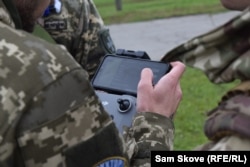 Soldiers training at the Kruk drone school watch the piloting controls for a drone.