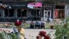 Local residents sit in front of damaged shops in Izyum on September 28, following liberation by Ukrainian forces.