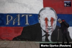 A mural of Russian President Vladimir Putin with the word 'Brother' written on it, which has been vandalized with red spray paint, in Belgrade.